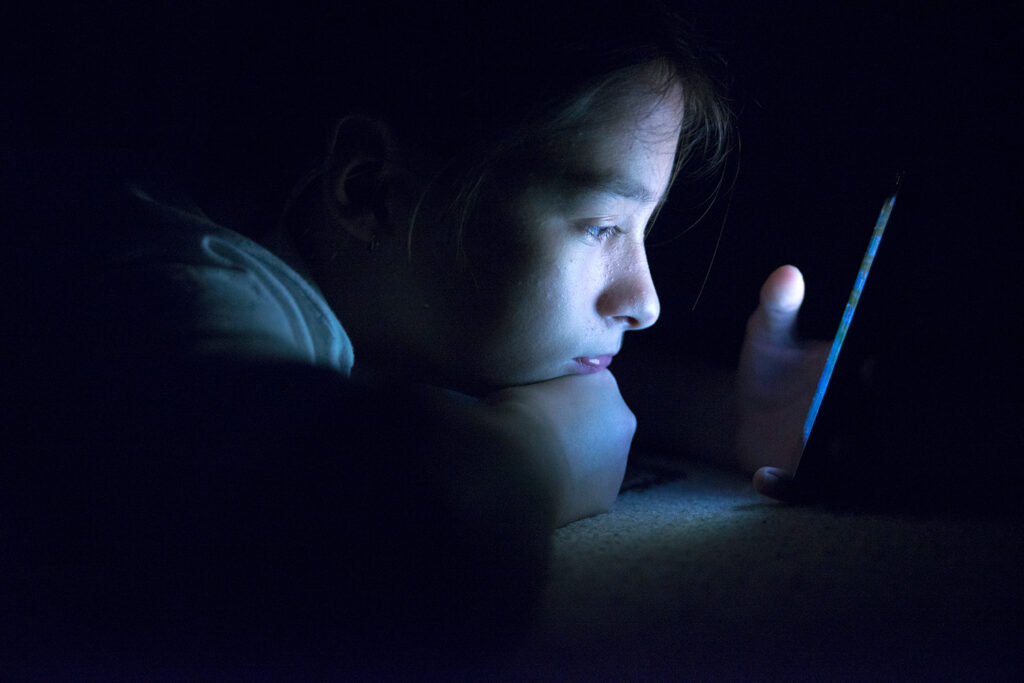 Solicitation of a Minor in MN, youth looking at mobile device screen in the dark