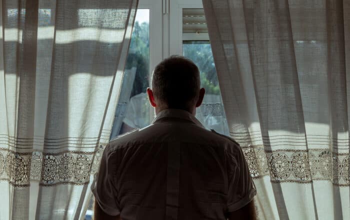 man standing, looking out a window, criminal consequences in minnesota