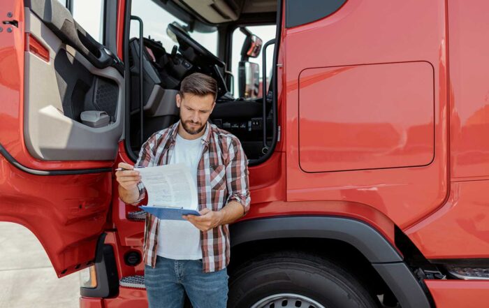 trucking regulations, red semi truck, and trucking company dispatcher reading from a clipboard